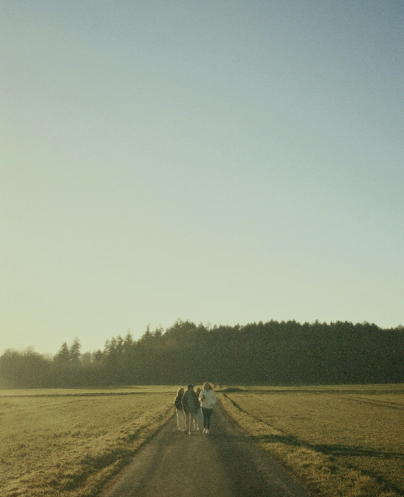 Tre persone camminano lungo una strada di campagna al tramonto